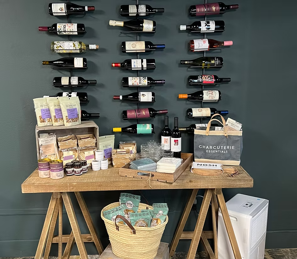 The Cape wine wall with bottles and charcuterie essentials on a wooden table